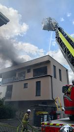 Feuerwehr löscht Brand mit Drehleiter in einem Wohnhaus in Wien, Rauch steigt auf.